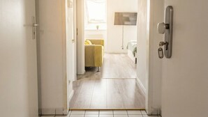A hallway leading to a room with a bed, a TV, and a window with curtains. - Modern Apartment in The Heart of Vienna 9 (Vienna)