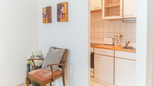 A kitchen with white cabinets, a toaster, and a vase with flowers. - Modern Apartment in The Heart of Vienna 9 (Vienna)