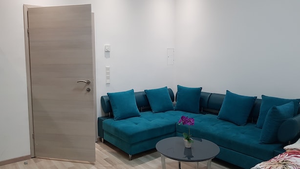A modern living room with a teal sofa, a small round table, and a wooden door. - Modern Apartment Vienna Congress Center (Vienna)
