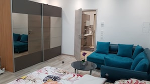 A modern living room with a blue sofa, a floral-patterned rug, and a large wardrobe with mirrored doors. - Modern Apartment Vienna Congress Center (Vienna)
