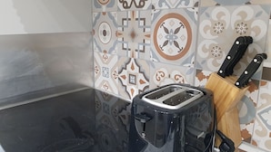 A kitchen with a black toaster, a wooden cutting board, and a knife block. - Modern Apartment Vienna Congress Center (Vienna)