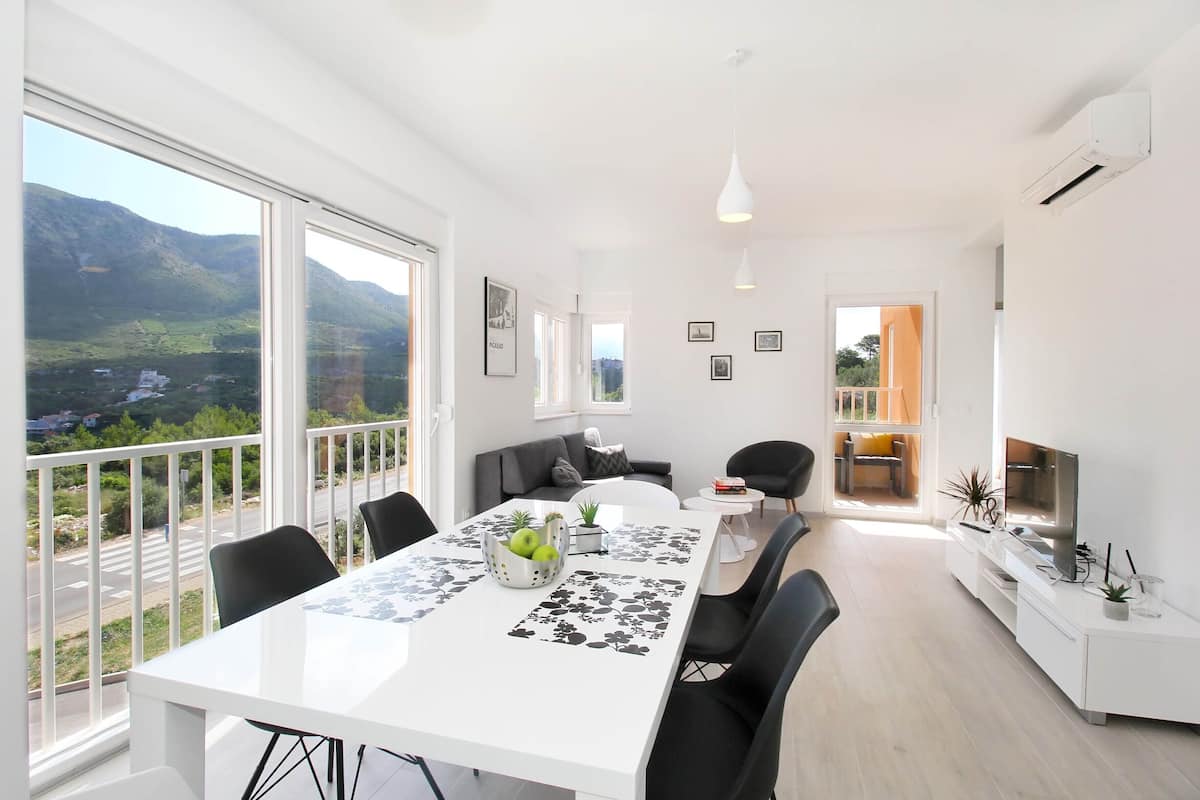 Una sala de estar moderna con comedor, ventanas grandes y vistas a las montañas.