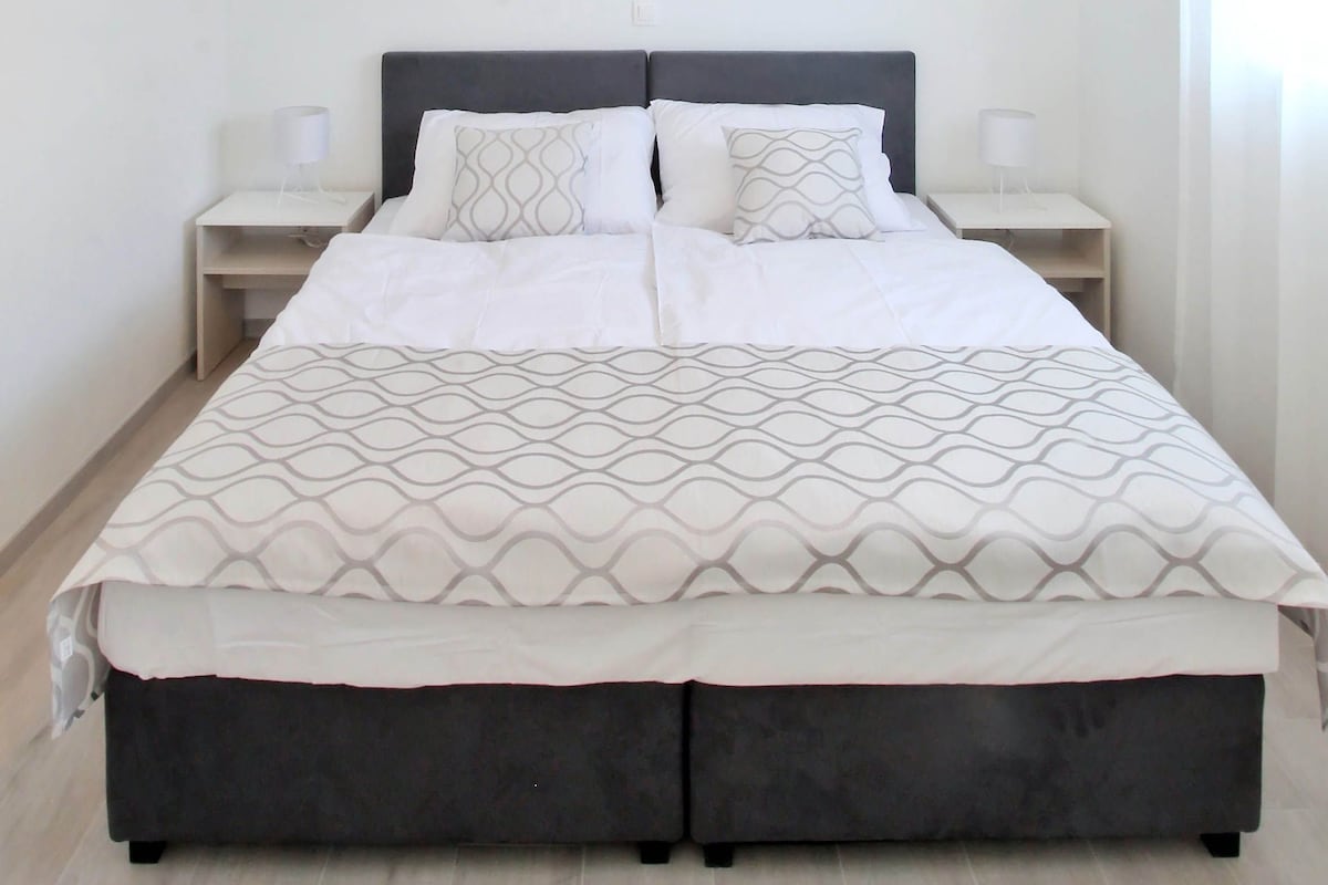Un dormitorio moderno con una cama grande, dos mesitas de noche y una lámpara colgante.