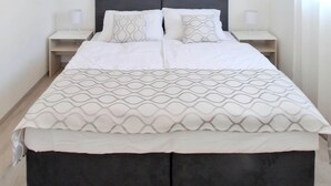 A modern bedroom with a large bed, two bedside tables, and a hanging light fixture. - Bacan Family Apartments (Konavle)