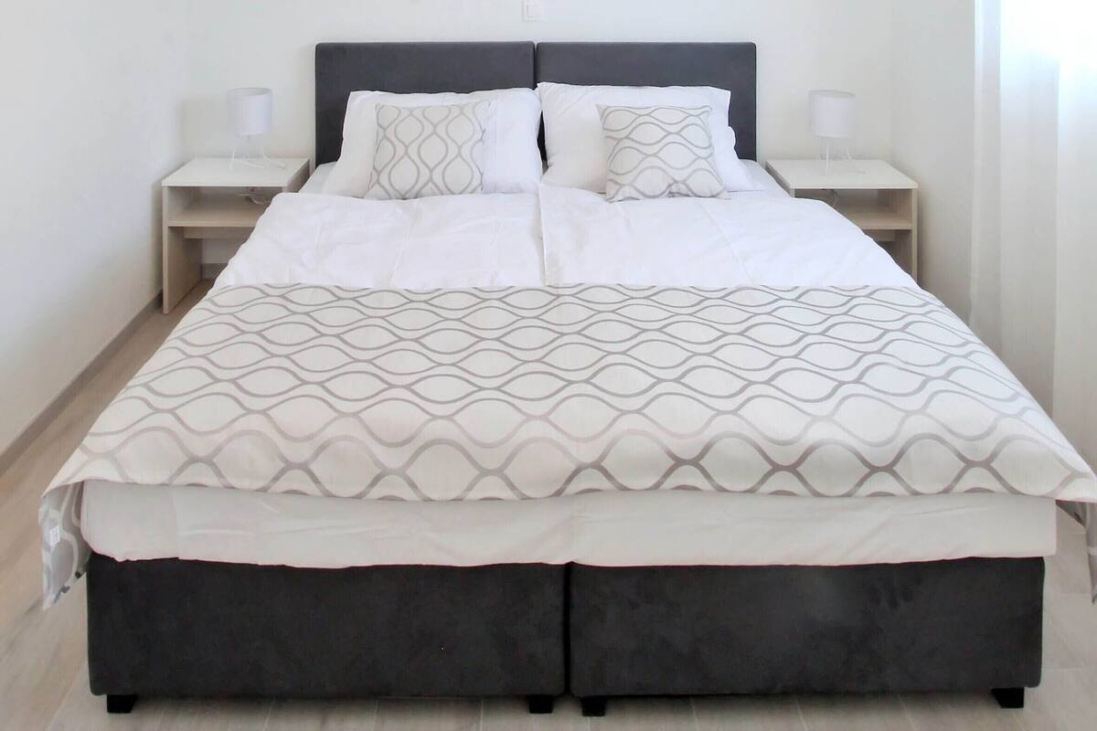 Un dormitorio moderno con una cama grande, dos mesitas de noche y una lámpara colgante.