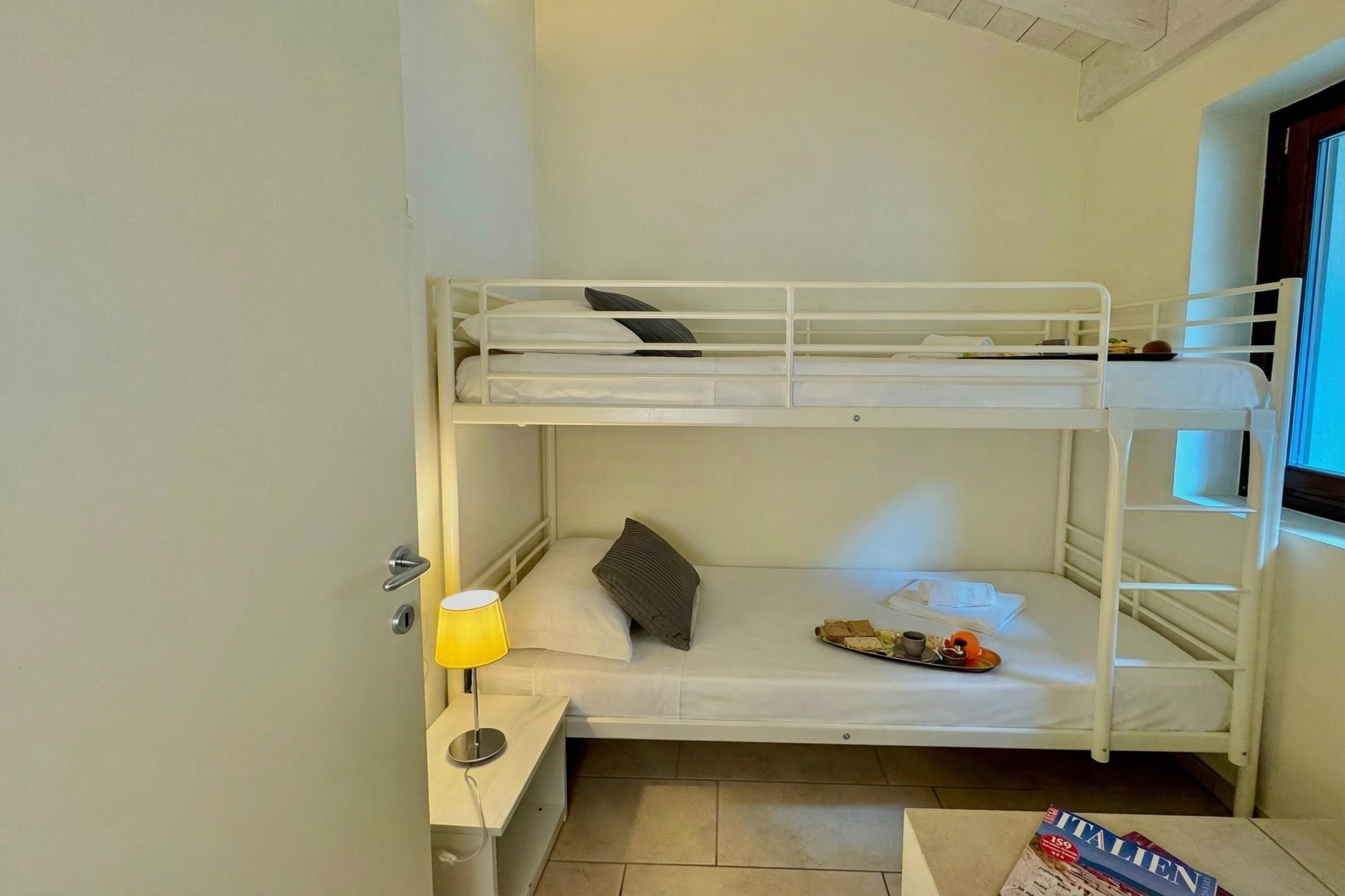 A bunk bed room with a desk, a lamp, and a magazine.