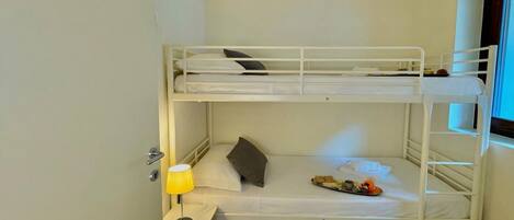 A bunk bed room with a desk, a lamp, and a magazine.