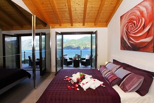 Un dormitorio con una cama grande, un balcón con vista al mar y un cuadro de una rosa en la pared.