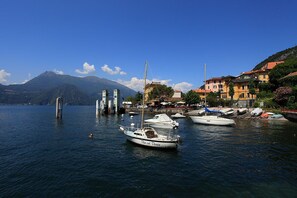 Un puerto deportivo con barcos amarrados, una montaña al fondo y edificios a lo largo de la costa.