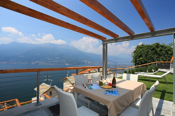 Una terraza con una mesa preparada para dos, con vistas a un lago y montañas.