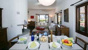 A dining area with a table set for four, including plates, cutlery, glasses, and a fruit bowl.