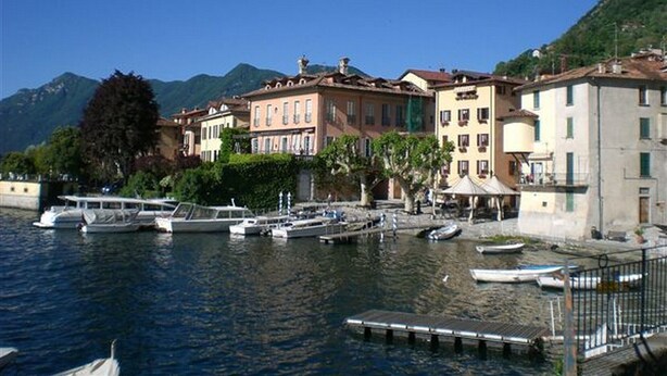 A waterfront area with buildings, boats, and mountains in the background.