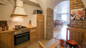 A kitchen with a stove, oven, microwave, and wooden cabinets. - Nobiallo Fantastico (Menaggio)