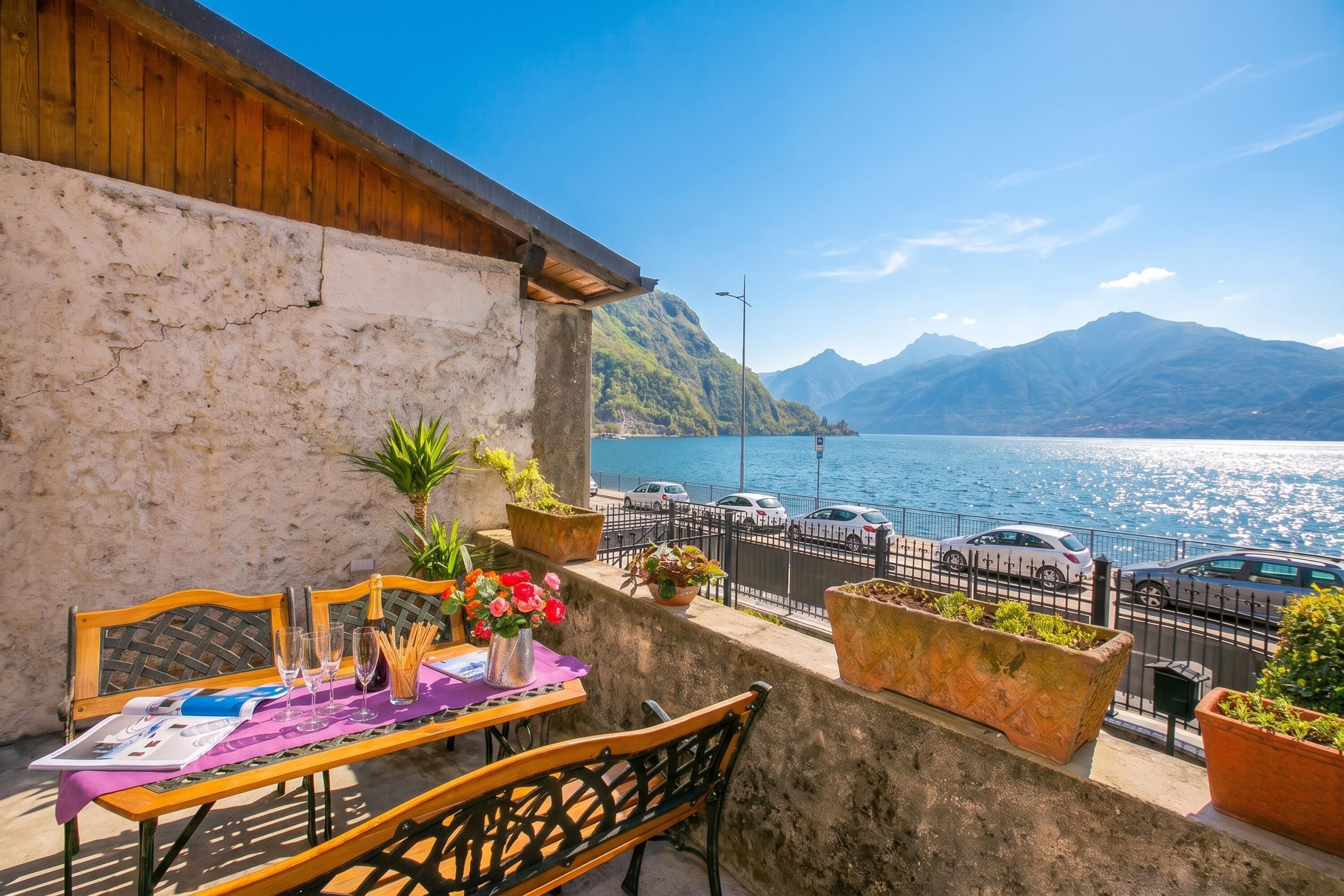 Un balcon avec une table dressée pour le dîner, offrant une vue sur un plan d’eau et des montagnes.