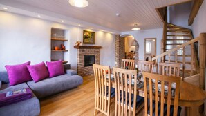 A living room with a grey sofa, purple cushions, wooden dining chairs, a brick fireplace, and a wooden staircase. - Nobiallo Fantastico (Menaggio)
