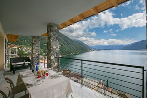 A dining area with a table set for two, overlooking a lake with mountains in the background.