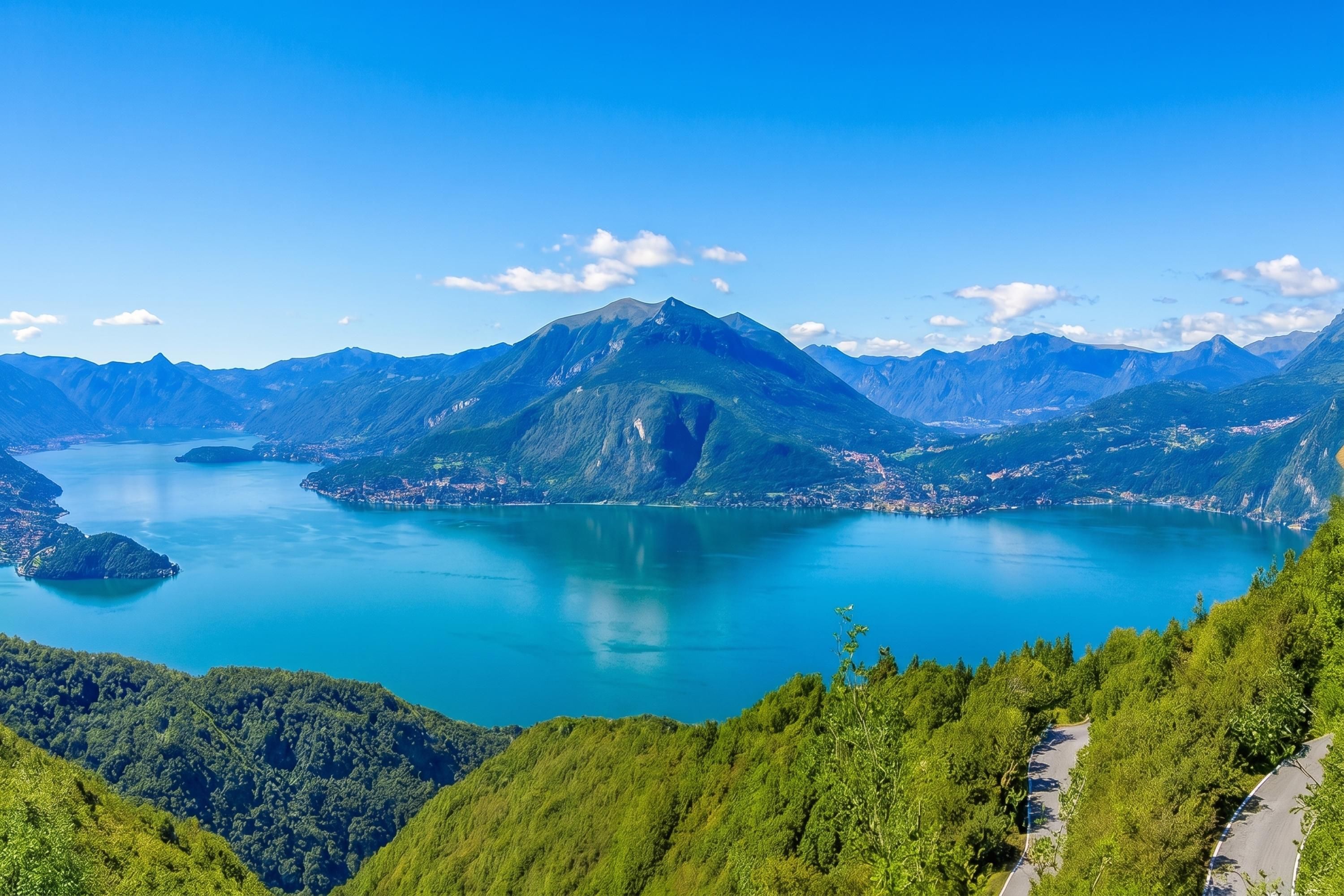 A mountainous landscape with a lake, a winding road, and a clear sky.