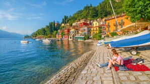 A waterfront scene with boats, a cobblestone path, and colorful buildings.