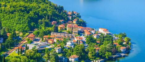 A coastal town with buildings along the shoreline, a small island in the background, and a clear blue sky.