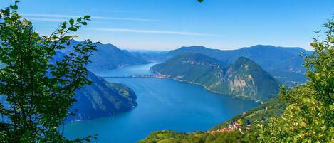 Un paysage montagneux avec un lac, entouré de verdure et de bâtiments situés au loin.
