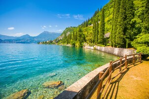 A clear lake with a wooden walkway and a stone railing.