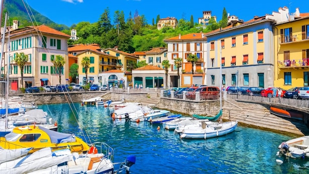 Un puerto deportivo con barcos, un muelle de piedra y edificios coloridos con balcones.