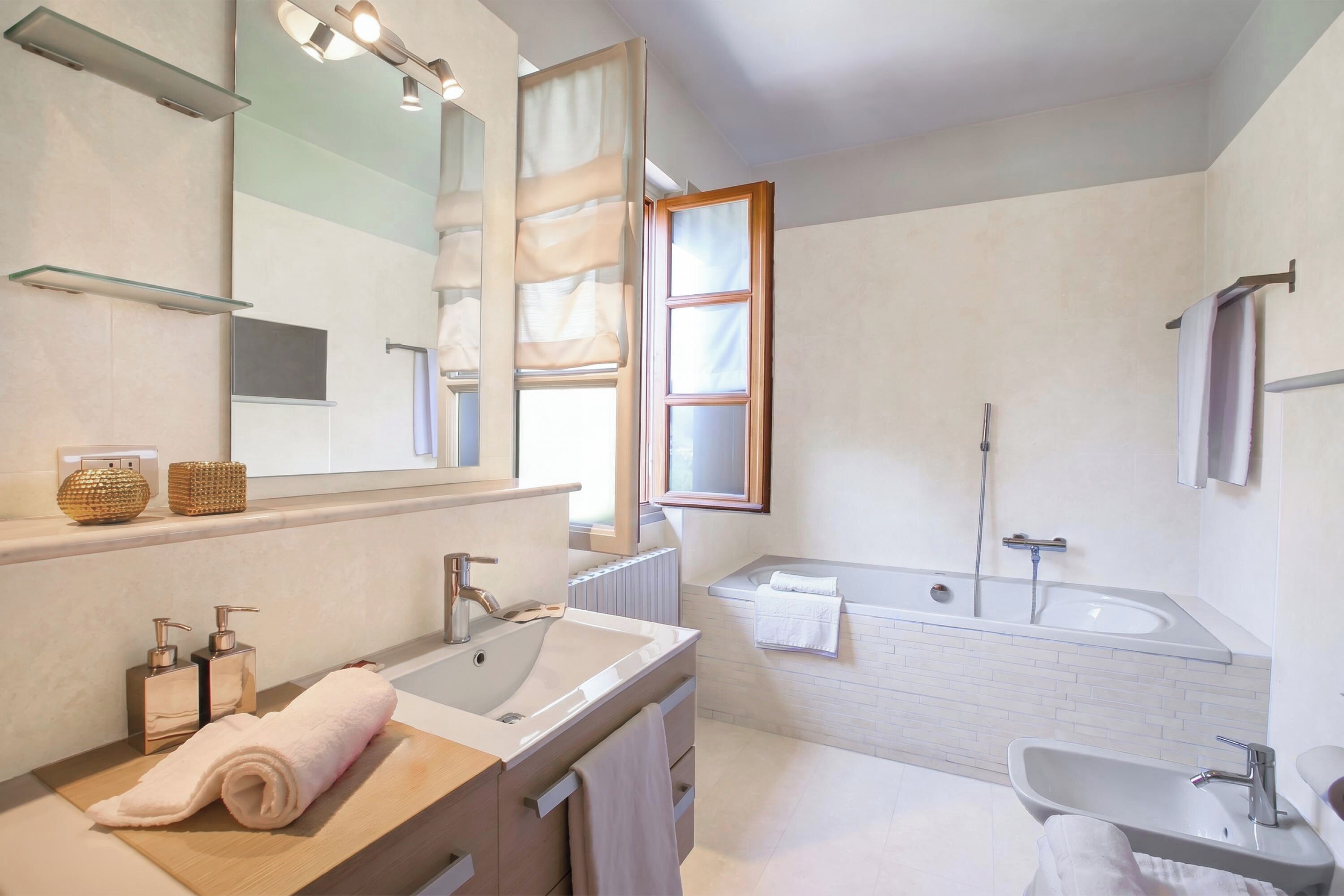 A modern bathroom with a large mirror, a bathtub, a sink, and a vanity.