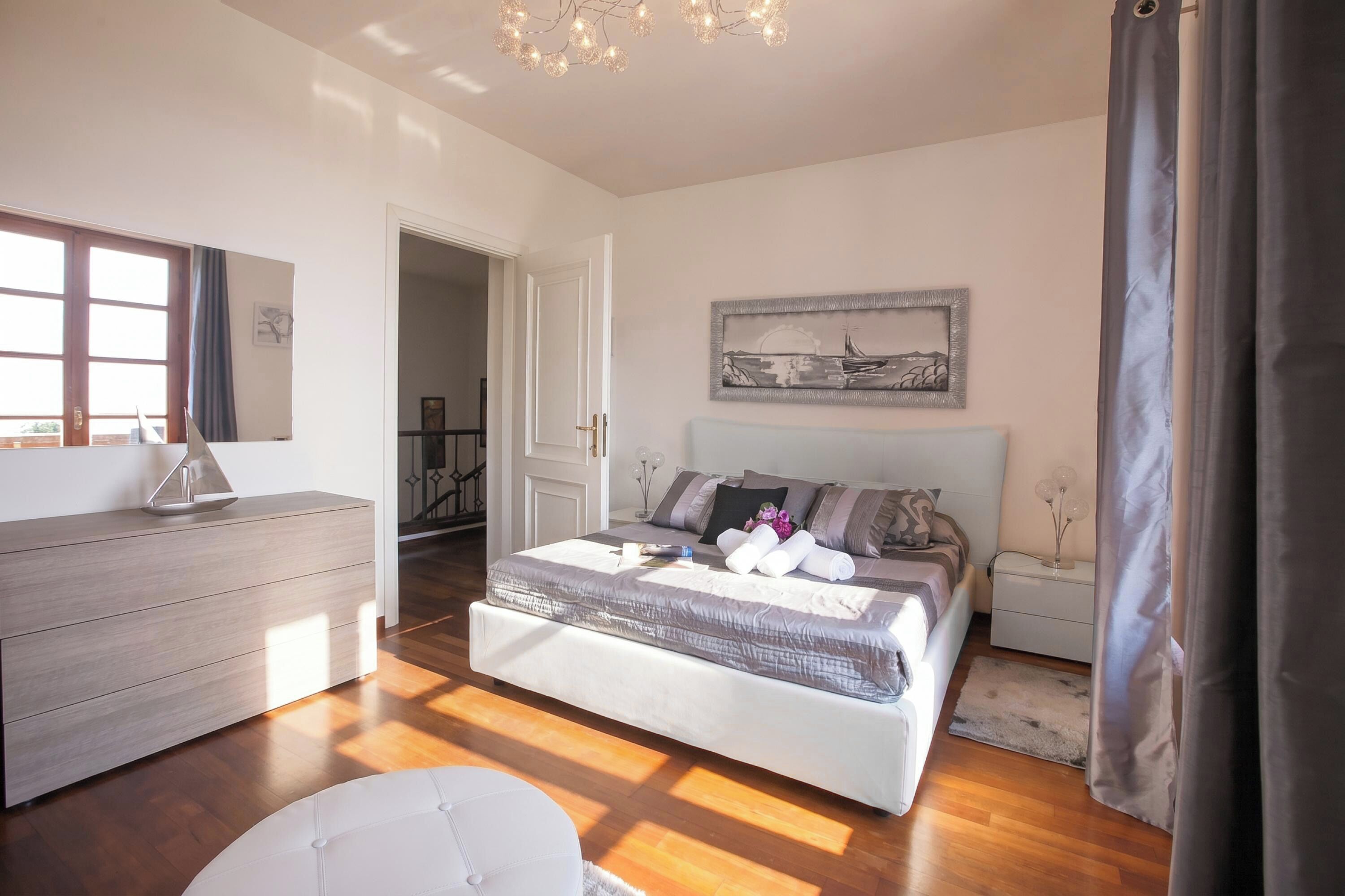 Une chambre à coucher avec un lit, des tables de chevet, une commode, un miroir et un tableau accroché au mur.