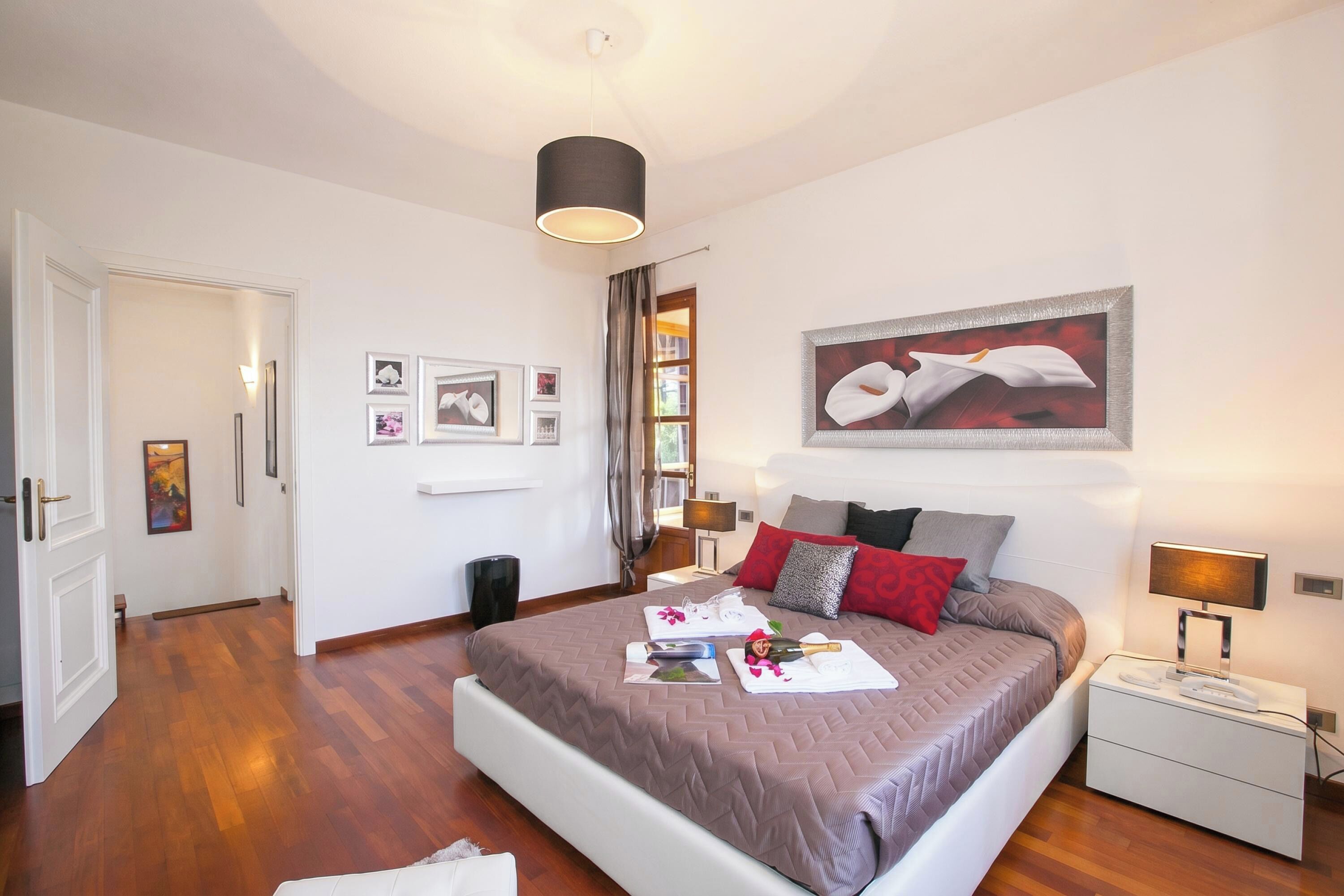 A bedroom with a bed, bedside table, lamp, and artwork on the wall.