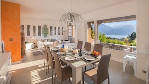 Comedor con una mesa dispuesta para seis comensales, una araña y vistas a las montañas.