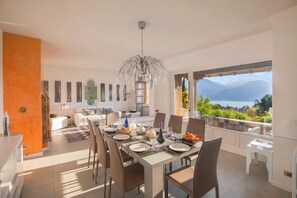 A dining area with a table set for six, a chandelier, and a view of mountains. - Villa Lakecomo - Ritrovo (Menaggio)