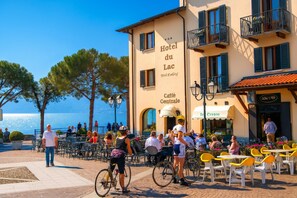 A coastal hotel with outdoor seating, a visible entrance, and a view of the sea.