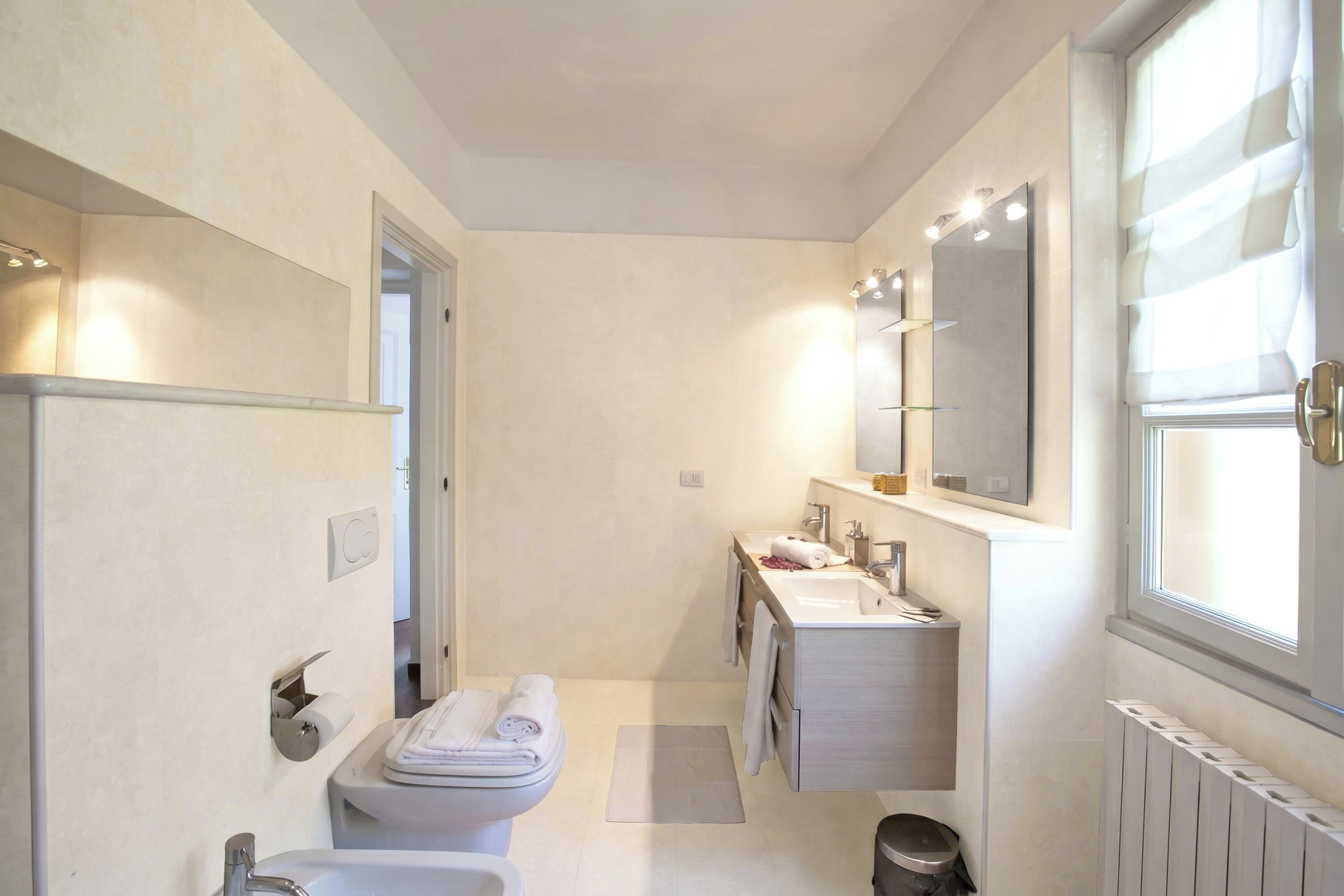 A modern bathroom with a toilet, sink, and mirror.