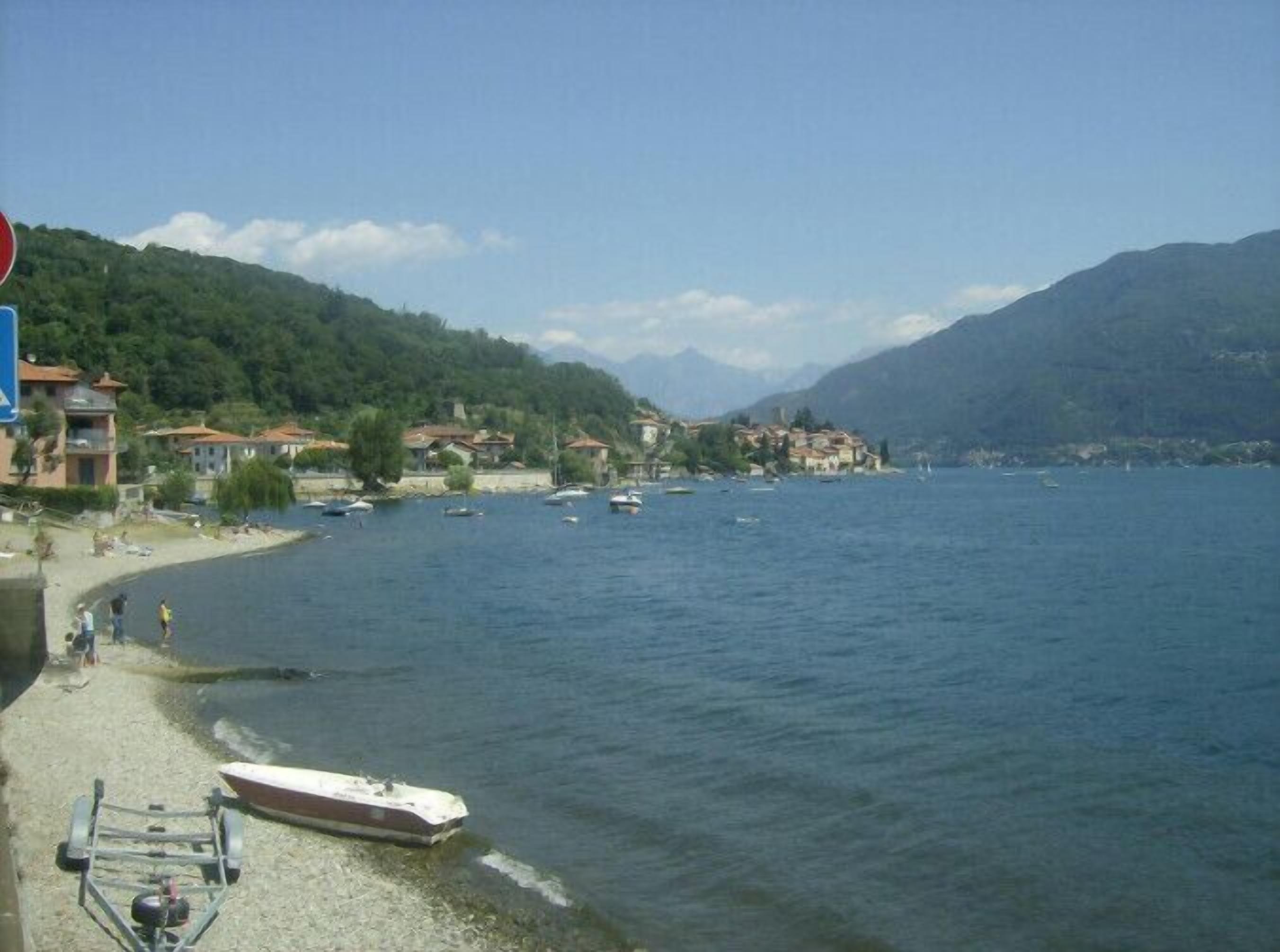 Une vue sur le lac, avec des bateaux, une plage et des bâtiments en arrière-plan.