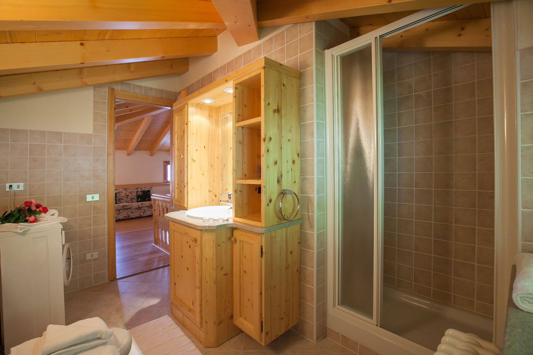A wooden cabin interior with a bathroom featuring a shower enclosure and a sink.