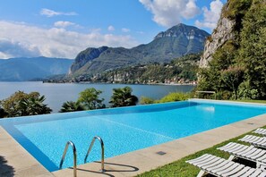 A swimming pool with clear blue water, surrounded by lounge chairs and a mountainous backdrop. - Gaeta 'Bellavista' (San Siro)