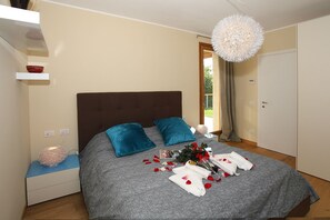 A bedroom with a bed, a bedside table, a hanging light fixture, and a door.