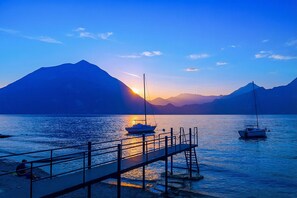 Un lac paisible, avec des bateaux, un quai et des montagnes en arrière-plan.