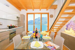 Una cocina moderna con comedor, techo de madera, ventanas amplias y vistas a la montaña, además de una escalera.