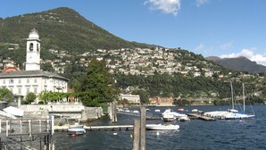 Un puerto con barcos, un faro y un pueblo en la ladera de una colina.