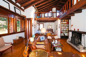 Un salón comedor espacioso, con techo de madera, chimenea, estantería y zona de comedor.