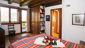 A bedroom with a bed, a bookshelf, a window, and a door.