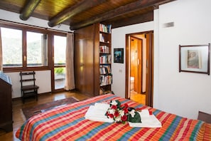 Un dormitorio con cama, estantería, ventana y puerta.