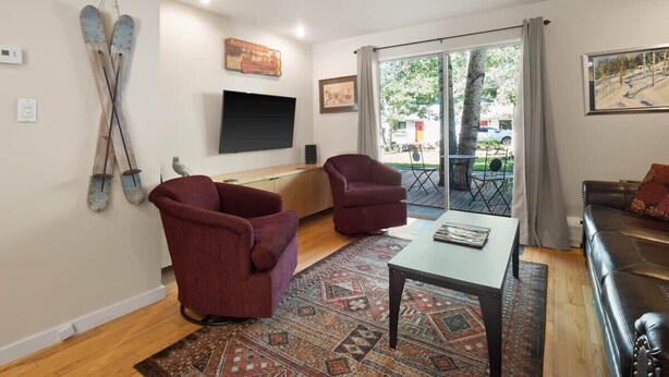 A living room with a sofa, two armchairs, a coffee table, a TV, and a large window with a view of the outdoors. - 2-BR Condo by Vail Resort: Outdoor Patio, Parking (Vail)