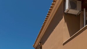 Una escalera que lleva a un edificio con fachada color beige, una puerta blanca y un equipo de aire acondicionado.