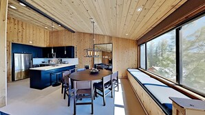 A modern kitchen with a central island, wooden walls, and a large window overlooking a forest. - Spacious 3 Bedroom Condo with Loft - Hike, Bike, Swim, Ski! by RedAwning (Mammoth Lakes)