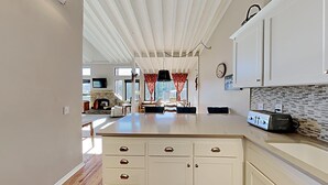 A modern kitchen with white cabinetry, a built-in stove, and a dining area with a large table and chairs. - Spacious 3 Bedroom Condo with Loft - Hike, Bike, Swim, Ski! by RedAwning (Mammoth Lakes)
