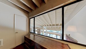 Ein Zimmer mit großem Fenster, Holzbalkendecke und einer Tür.