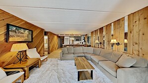 Un salón amplio con un sofá modular grande, una mesa de centro de madera y un comedor al fondo.