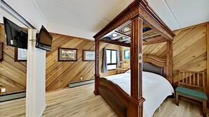 Una cama con dosel en una habitación con paredes de madera y techo inclinado.